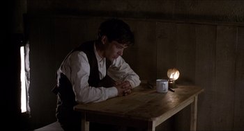 Movie still from “The Wind that Shakes the Barley” (2006), directed by Ken Loach – A man sitting at a wooden table with a cup of coffee; Medium shot, High angle
