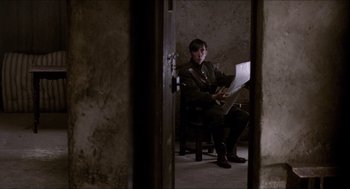 Movie still from “The Wind that Shakes the Barley” (2006), directed by Ken Loach – A man sitting in a chair holding a laptop; Medium shot, Low angle