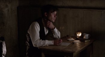 Movie still from “The Wind that Shakes the Barley” (2006), directed by Ken Loach – A man sitting at a table writing on a piece of paper; Medium shot, Low angle