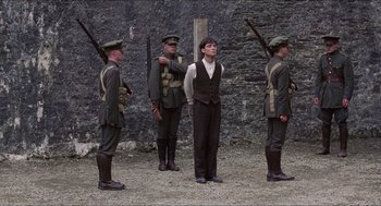 Movie still from “The Wind that Shakes the Barley” (2006), directed by Ken Loach – A group of men standing next to each other holding guns; Wide shot, Low angle