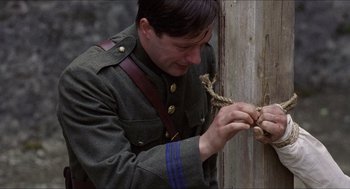 Movie still from “The Wind that Shakes the Barley” (2006), directed by Ken Loach – A man in a military uniform tying a rope around a wooden post; Close Up shot, Low angle