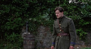 Movie still from “The Wind that Shakes the Barley” (2006), directed by Ken Loach – A man in a military uniform standing next to a barrel; Medium shot, Low angle