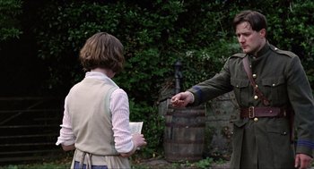 Movie still from “The Wind that Shakes the Barley” (2006), directed by Ken Loach – A man handing something to another man in a field; Medium shot, Over the shoulder angle