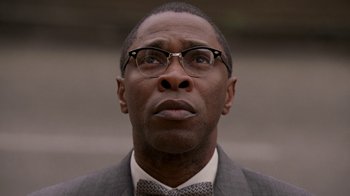 Movie still from “The Wire” (2002), created by David Simon – A person wearing a suit and glasses; Close Up shot, Low angle