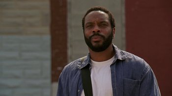 Movie still from “The Wire” (2002), created by David Simon – A man in a white shirt and a blue jacket; Close Up shot, Low angle