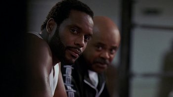 Movie still from “The Wire” (2002), created by David Simon – A man and a bald man are posing for a picture; Close Up shot, Low angle