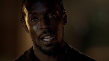 Movie still from “The Wire” (2002), created by David Simon – A man's face in a dimly - lit room; Close Up shot, Low angle