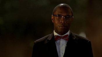 Movie still from “The Wire” (2002), created by David Simon – A man in a suit and a bow tie; Close Up shot, Low angle