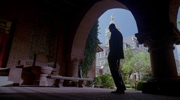 Movie still from “The Wire” (2002), created by David Simon – A man standing under an archway in front of a building; Extreme Wide shot, Low angle