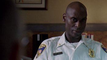 Movie still from “The Wire” (2002), created by David Simon – A man in a white uniform is looking to his left; Close Up shot, Low angle