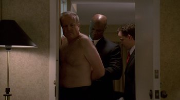 Movie still from “The Wire” (2002), created by David Simon – A man in a suit and tie standing next to another man in a suit and tie; Medium shot, Over the shoulder angle