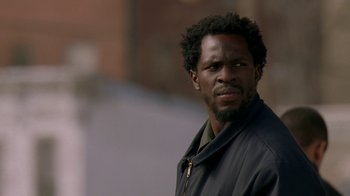 Movie still from “The Wire” (2002), created by David Simon – A man with a beard is looking at the camera; Close Up shot, Low angle