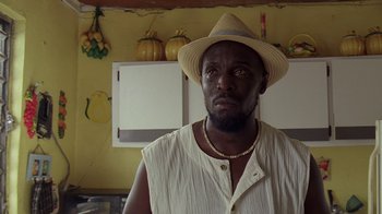 Movie still from “The Wire” (2002), created by David Simon – A man wearing a straw hat in a kitchen; Close Up shot, Low angle