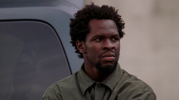 Movie still from “The Wire” (2002), created by David Simon – A person wearing a green shirt; Close Up shot, Low angle