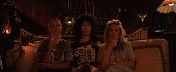 Movie still from “The Witches of Eastwick” (1987), directed by George Miller – A group of women sitting next to each other in a room; Medium shot, Low angle
