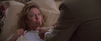 Movie still from “The Witches of Eastwick” (1987), directed by George Miller – A woman in a hospital bed being examined by a doctor; Close Up shot, Over the shoulder angle
