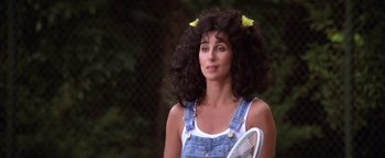 Movie still from “The Witches of Eastwick” (1987), directed by George Miller – A woman with a tennis racquet in her hair; Close Up shot, Over the shoulder angle