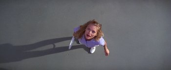 Movie still from “The Witches of Eastwick” (1987), directed by George Miller – A woman holding a tennis racquet on a tennis court; Medium shot, Overhead angle