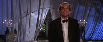 Movie still from “The Witches of Eastwick” (1987), directed by George Miller – A person wearing a suit and bow tie; Medium shot, Low angle