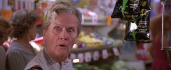 Movie still from “The Witches of Eastwick” (1987), directed by George Miller – An older woman looking surprised in a grocery store; Close Up shot, Low angle