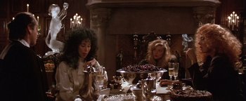 Movie still from “The Witches of Eastwick” (1987), directed by George Miller – Two women sitting at a dinner table in front of a bowl of cherries; Medium shot, Low angle
