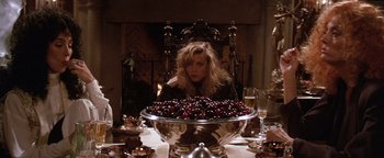 Movie still from “The Witches of Eastwick” (1987), directed by George Miller – A woman sitting in front of a large bowl of cherries; Medium shot, High angle