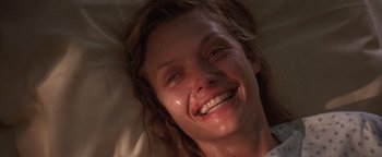 Movie still from “The Witches of Eastwick” (1987), directed by George Miller – A person laying in a bed smiling; Close Up shot, Overhead angle