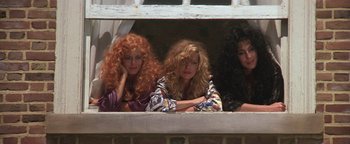 Movie still from “The Witches of Eastwick” (1987), directed by George Miller – A group of women sitting next to each other on a ledge; Medium shot, Low angle