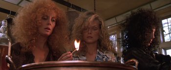 Movie still from “The Witches of Eastwick” (1987), directed by George Miller – A woman lighting a match in front of another woman; Close Up shot, Low angle