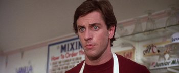 Movie still from “The Witches of Eastwick” (1987), directed by George Miller – A person wearing an apron and looking surprised; Close Up shot, Low angle