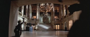 Movie still from “The Witches of Eastwick” (1987), directed by George Miller – A large staircase with a chandelier in the middle of it; Extreme Wide shot, High angle