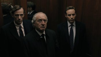 Movie still from “The Wizard of Lies” (2017), directed by Barry Levinson – A group of men standing next to each other in suits; Medium shot, Low angle