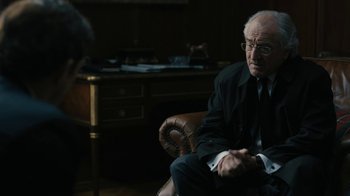 Movie still from “The Wizard of Lies” (2017), directed by Barry Levinson – An older man sitting in a chair in front of a desk; Medium shot, Over the shoulder angle