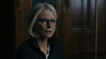 Movie still from “The Wizard of Lies” (2017), directed by Barry Levinson – An older woman wearing glasses and a black jacket; Close Up shot, Over the shoulder angle