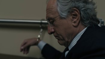 Movie still from “The Wizard of Lies” (2017), directed by Barry Levinson – An older man in a business suit holding a pair of handcuffs; Close Up shot, Over the shoulder angle