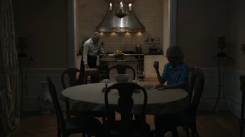 Movie still from “The Wizard of Lies” (2017), directed by Barry Levinson – A man and a woman sitting at a dining room table; Wide shot, High angle