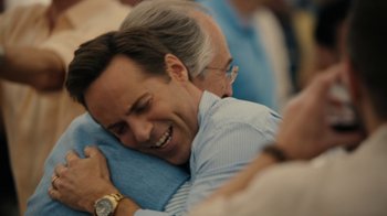 Movie still from “The Wizard of Lies” (2017), directed by Barry Levinson – A man is hugging another man in a crowd; Close Up shot, Over the shoulder angle