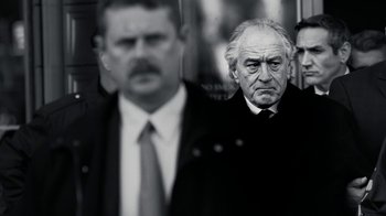 Movie still from “The Wizard of Lies” (2017), directed by Barry Levinson – A black and white photo of a man in a suit and tie; Close Up shot, Low angle