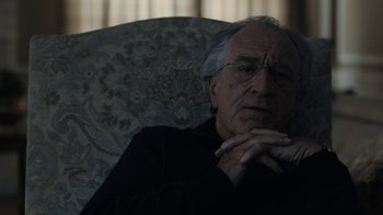 Movie still from “The Wizard of Lies” (2017), directed by Barry Levinson – An older man sitting in a chair with his hand on his chin; Close Up shot, Over the shoulder angle
