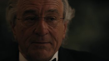 Movie still from “The Wizard of Lies” (2017), directed by Barry Levinson – An older man wearing glasses and a suit; Close Up shot, Over the shoulder angle