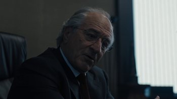 Movie still from “The Wizard of Lies” (2017), directed by Barry Levinson – An older man wearing a suit and tie; Close Up shot, Over the shoulder angle