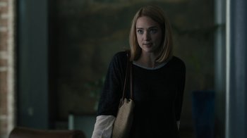Movie still from “The Wizard of Lies” (2017), directed by Barry Levinson – A woman with a purse standing in a dark room; Medium shot, Over the shoulder angle