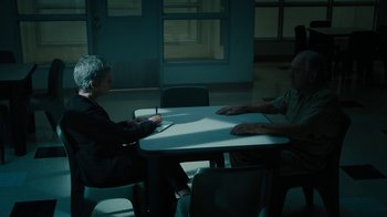 Movie still from “The Wizard of Lies” (2017), directed by Barry Levinson – Two people sitting at a table in a room; Wide shot, High angle