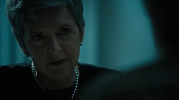 Movie still from “The Wizard of Lies” (2017), directed by Barry Levinson – An older woman wearing a black shirt and a pearl necklace; Close Up shot, Over the shoulder angle