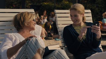 Movie still from “The Wizard of Lies” (2017), directed by Barry Levinson – Two women sitting on lawn chairs on the beach; Medium shot, Over the shoulder angle