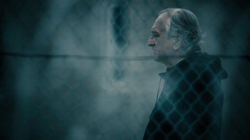 Movie still from “The Wizard of Lies” (2017), directed by Barry Levinson – An older man standing in front of a chain link fence; Close Up shot, Low angle