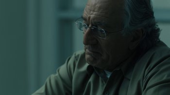 Movie still from “The Wizard of Lies” (2017), directed by Barry Levinson – An older man wearing glasses looking at the camera; Close Up shot, Over the shoulder angle