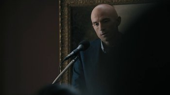 Movie still from “The Wizard of Lies” (2017), directed by Barry Levinson – A man with bald head is speaking into a microphone; Close Up shot, Over the shoulder angle