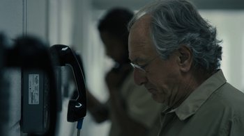 Movie still from “The Wizard of Lies” (2017), directed by Barry Levinson – An older man looking at a phone in a room; Close Up shot, Over the shoulder angle