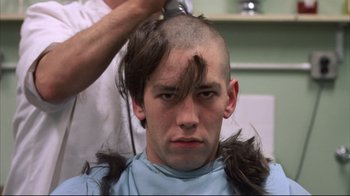 Movie still from “Full Metal Jacket” (1987), directed by Stanley Kubrick – A young man getting his head shaved in a barber shop; Close Up shot, Over the shoulder angle